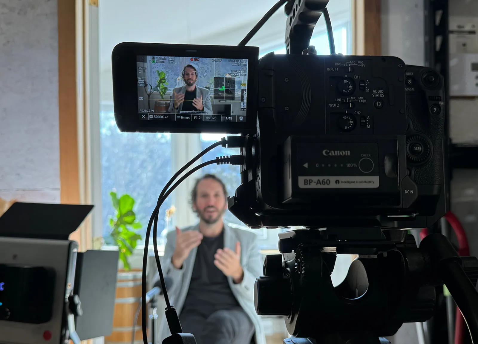 Tournage OXXY en cours — caméra cinéma cadrée sur une personne en pleine conversation, montée chez le client